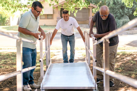 three men work to build an accessibility ramp