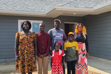 new Habitat homeowners and their family pose in front of their new home