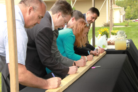 people signing a board that will be used by Southeast Tech students to build a Habitat home