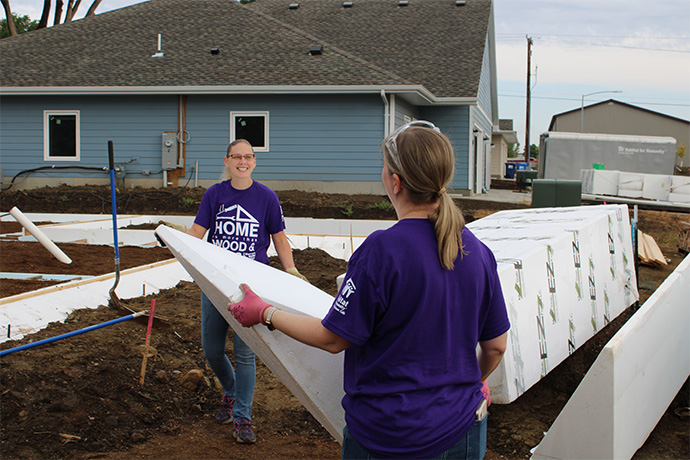 two women wearing women build t-shirts smile as they move ICF forms