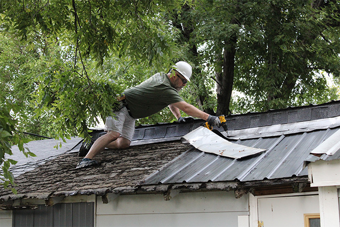 MasterBrand employee removes old shingles from the veteran's roof.