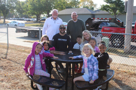 Students and staff at Terry Redlin smile with Habitat's Kevin Healy and State Farm's Bill Thompson at one of their brand-new picnic tables.