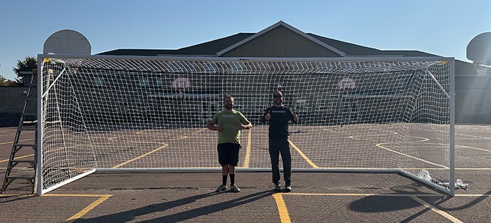 Habitat's Kevin Healy and Mike Sherron smile and give thumbs up under the soccer goal they delivered to Terry Redlin Elementary.