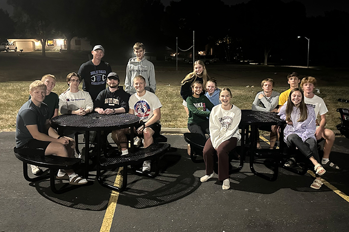 High school students and leaders from Good News Youth smile while sitting at the picnic tables they built for Terry Redlin Elementary.