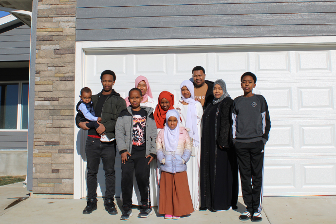 Ali and Rumiya stand with their eight children in front of their new home.