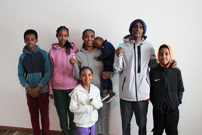 Hidray and Almaz smile with five of their six children while holding up keys to their new home.