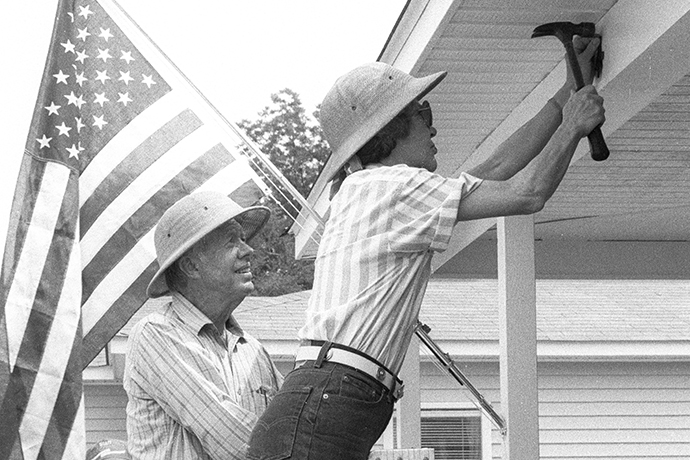 Jimmy smiles while watching Rosalynn hammer a nail at the Jimmy & Rosalynn Carter Work Project in 1987.