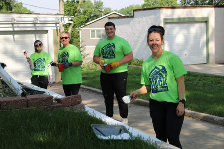 Habitat volunteers smile while painting a retaining wall.