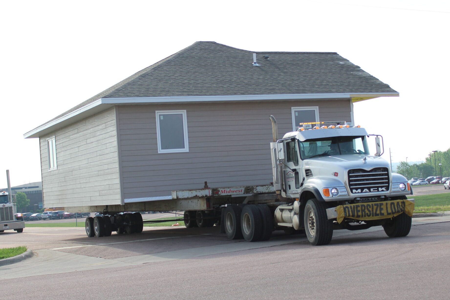 The home built by CTE Academy students during the 2024-25 school year is driven out of the school grounds on a truck to Habitat's lot.