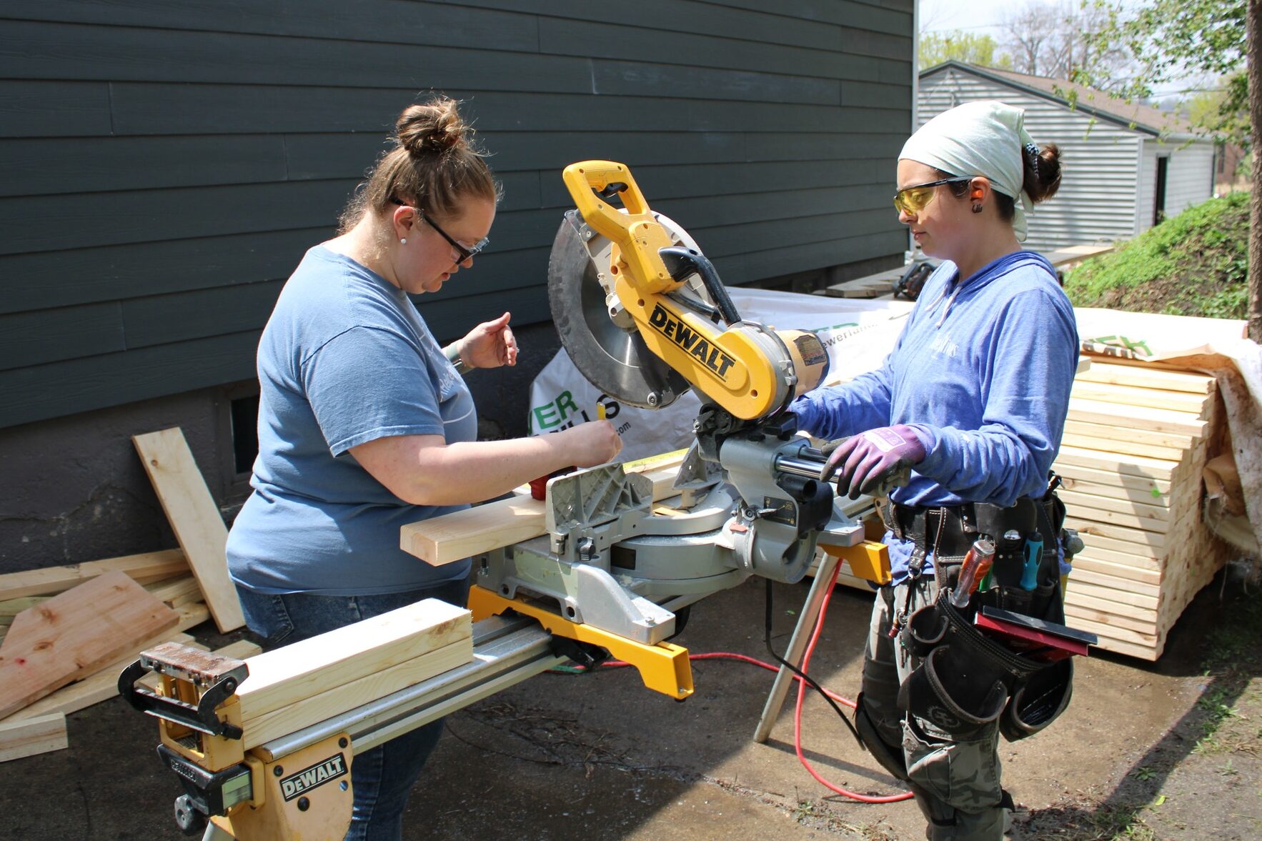 Habitat staff members Brittany and Jolynn measure and cut boards to frame walls inside of one of our rehab homes.