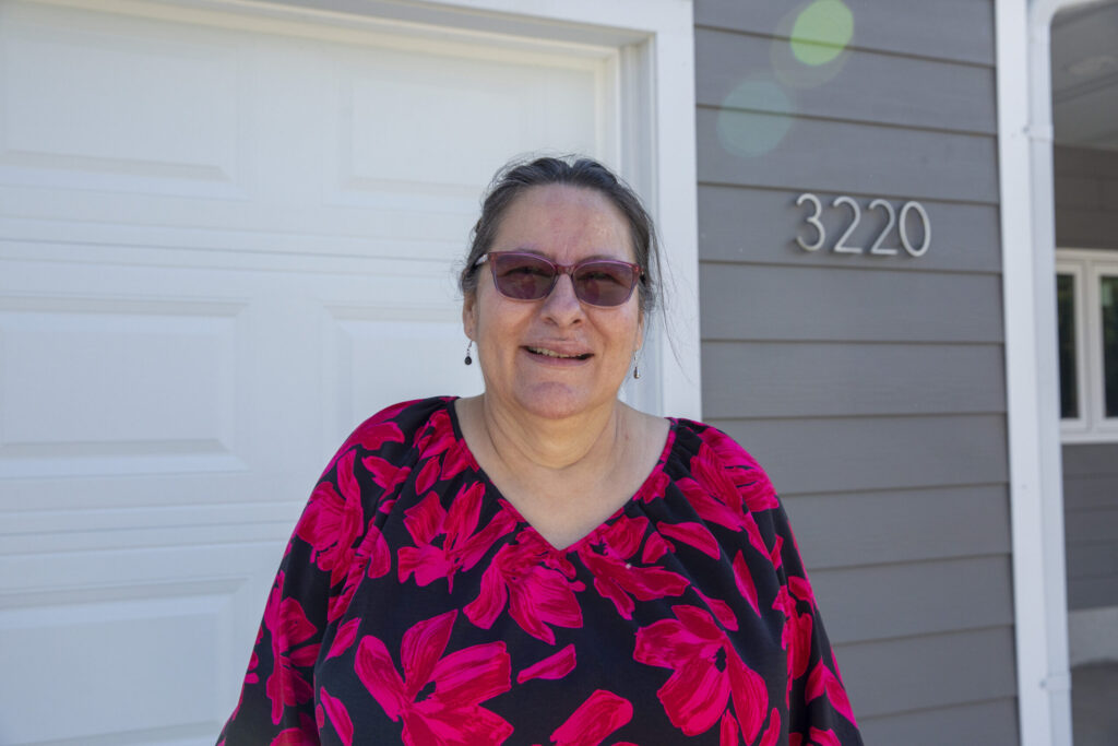 New homeowner Vickie smiles in front of her new home.