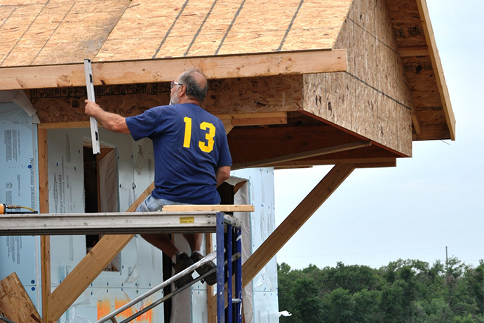 John Homstad sitting on scaffolding while working on a Habitat home