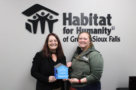 Habitat's volunteer coordinator Brittany Bandstra presents the 2025 John Homstad Volunteer of the Year award to Sheila Hoff.
