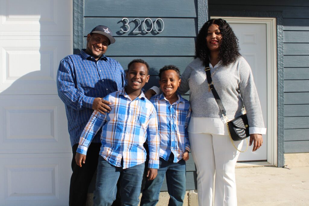 Mitiku and Emebet smile with their two sons in front of their new home.