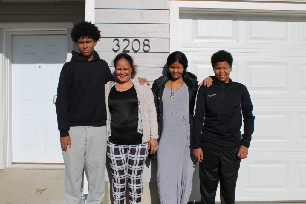 Okuba smiles with her three children in front of their new home.