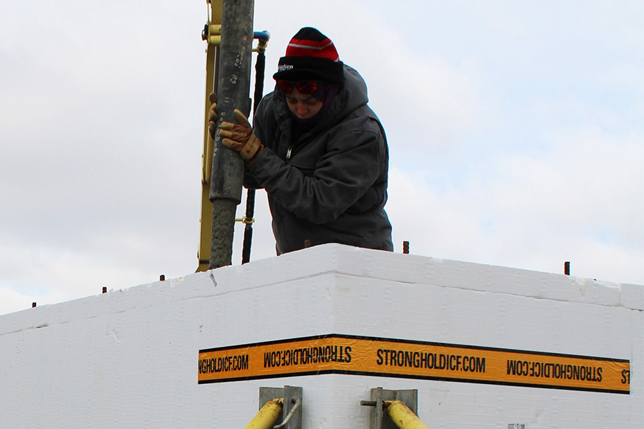 Habitat's construction supervisor Jolynn pours concrete into a Stronghold ICF foundation.