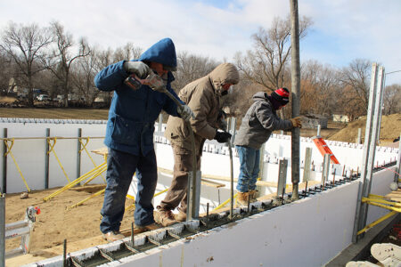 Habitat staff and volunteers fill a Stronghold ICF foundation with concrete and shake out air bubbles.