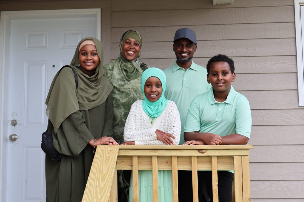 Abdo, Badria and their three children stand on the porch of their new home before their home dedication.