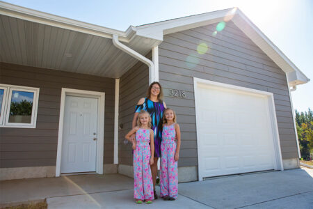 Homebuyer Dalonda stands in front of her new home with her two daughters.