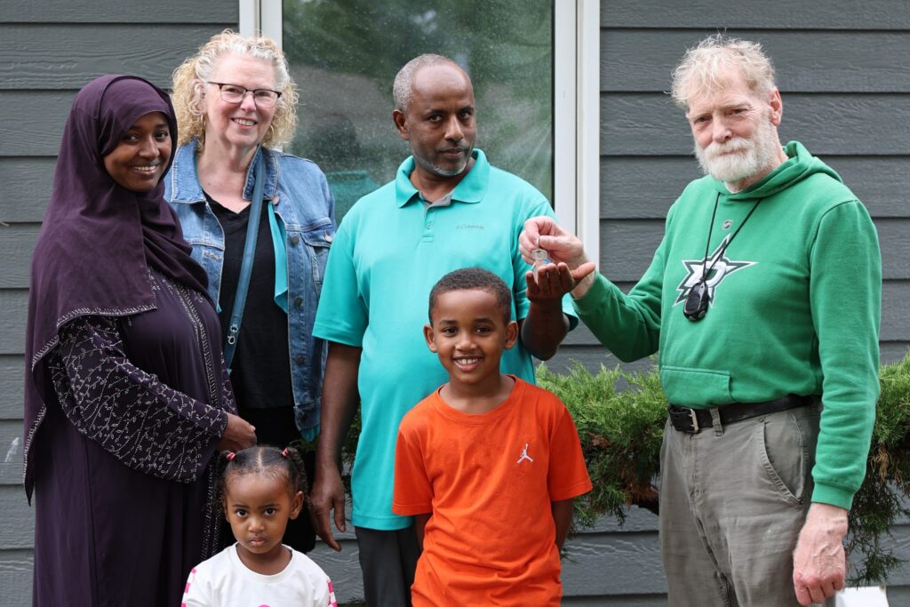 Adulkadir, Rahima and two of their children smile while receiving keys from the family that grew up in the home.