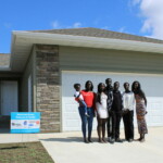 Rebecca and her family stand in front of their new home.