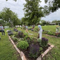 Volunteers add mulch to newly planted flowers and bushes in the Terrace Park community garden.