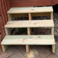 Unstained stairs attached to a cherry stained deck.