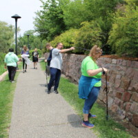 Volunteers with trash grabbers pick up trash and put it in a trash bag.