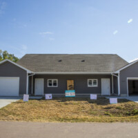 The exterior of the twin home. Signs are set up for the dedication.