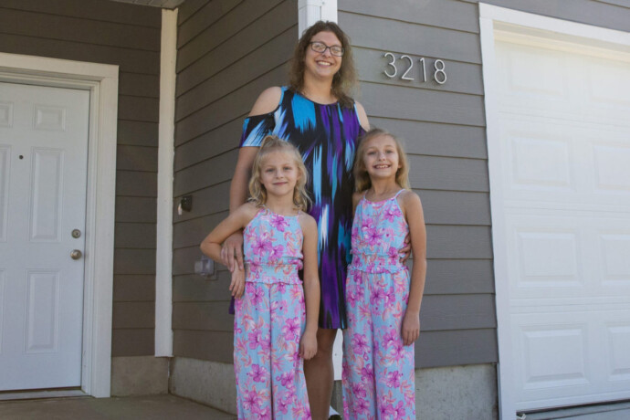 Dalonda stands with her two daughters in front of their new home.