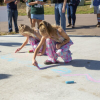 Dalonda's daughters crouch on the driveway of their new home to do sidewalk chalk.