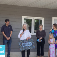 Linda holds up a doormat with the word "home" written on it during the dedication program.