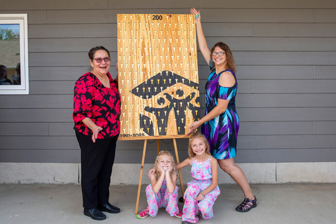 Twin home neighbors Vickie and Dalonda along with Dalonda's two daughters pose by a commemorative 200 homes key sign with the Habitat home emblem.