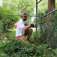 Our volunteers cleaned up this backyard with a lot of trimming and landscaping! A volunteer trims a vine from the fence.