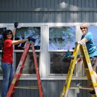 These windows looked squeaky clean when our volunteers were done with them! Volunteers smile while scaping debris and washing windows.