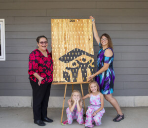 Vickie, Dalonda and Dalonda's daughters smile next to the key sign after they placed the 199th and 200th keys on the sign during their dedication.