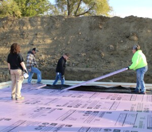 Volunteers lay down insulation boards in a Millard Acres foundation.