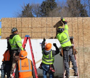 Volunteers put up sheeting on the garage of a Millard Acres twin home.