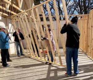 Volunteers move interior wall studs into place in a Millard Acres twin home.