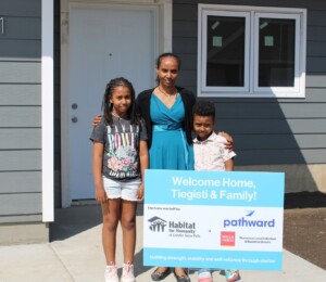 Tiegisti and her two children smile in front of their new Millard Acres home.