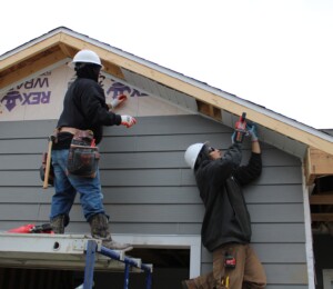 Volunteers add soffit and siding to a Millard Acres twin home.
