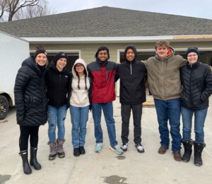 Volunteers smile in front of a Habitat Millard Acres twin home in April 2023.