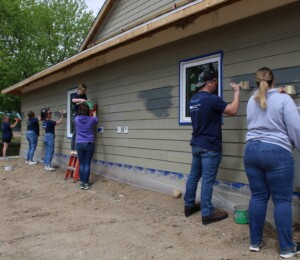 Volunteers paint the exterior siding of a Millard Acres twin home.