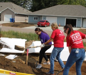 Women Build 2023 volunteers shovel dirt in a Millard Acres foundation.
