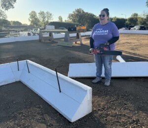 Future Habitat homebuyer Vickie holds a saw ready to cut ICF foundation block.