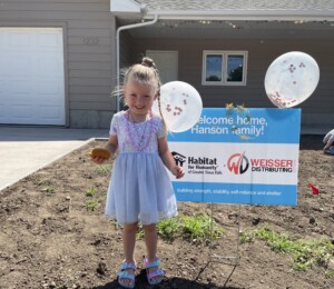 Dana's daughter smiles in front of her new home on dedication day.