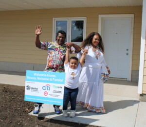 Neway, Netsanet and their son cheer in front of their new Millard Acres twin home.