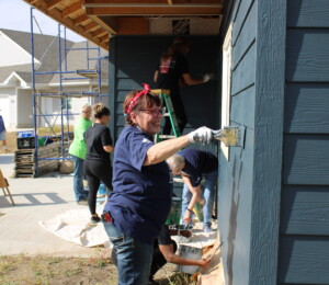 Women Build volunteers paint the exterior of a Millard Acres twin home.