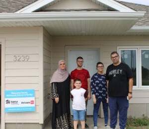 Mahmoud, Intesar and their three children smile outside of their new home.