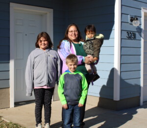 Liz and her grandchildren smile in front of their new Millard Acres twin home.